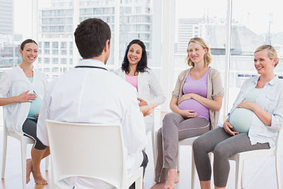 Group of pregnant women sit and talk with a doctor leading the group